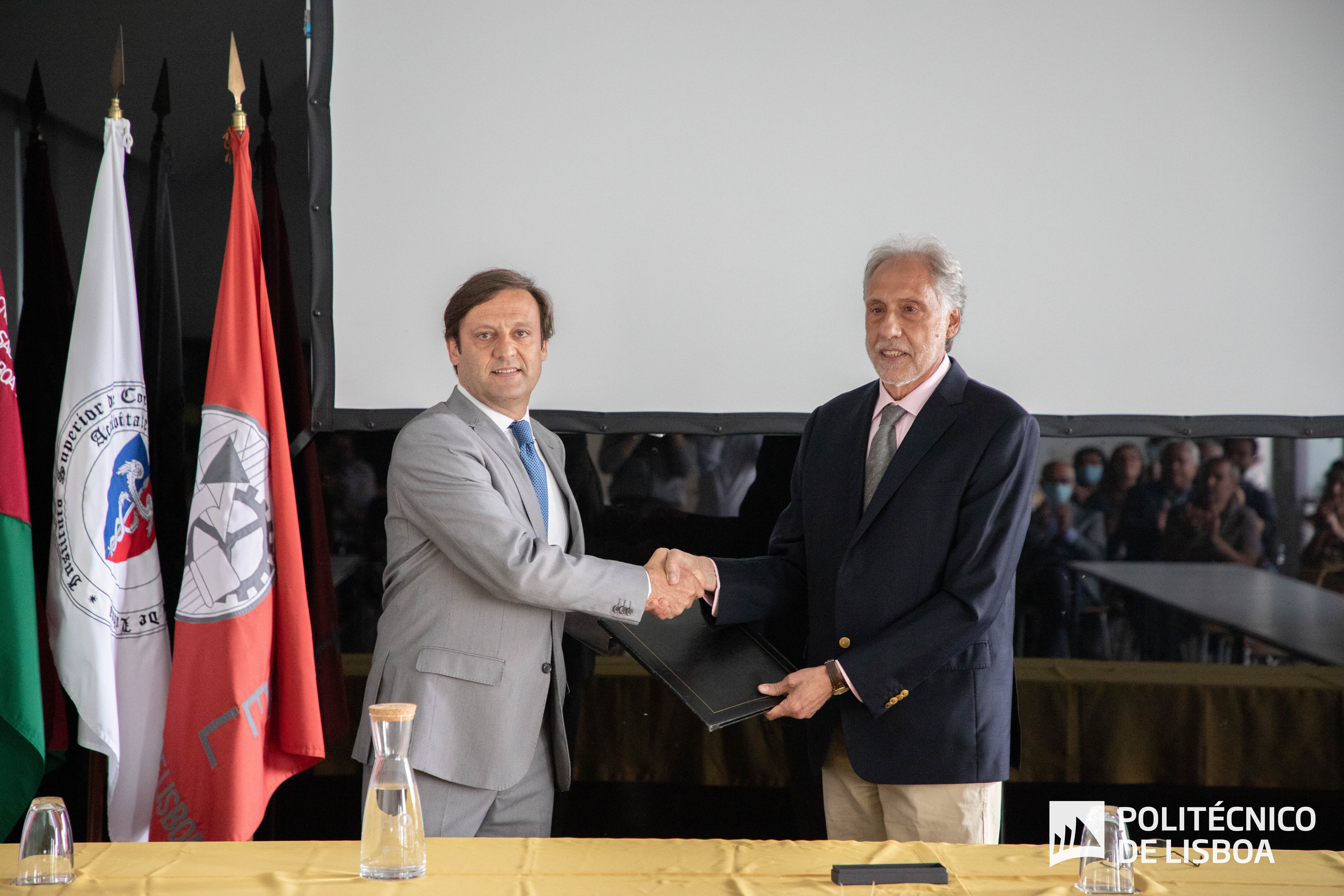 Foto com dois homens em pé a dar um aperto de mão